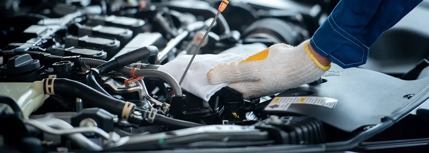 mechanic leaning over an engine checking oil levels